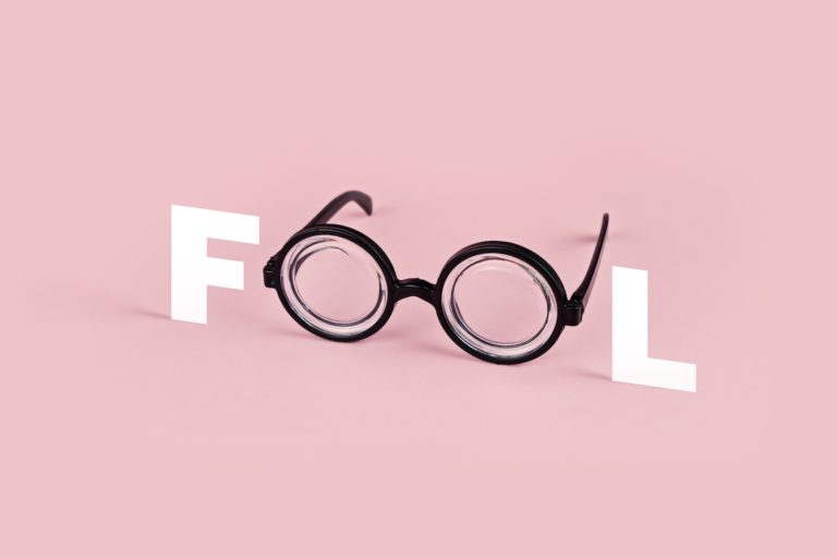 Funny goggles with round glasses on pink background and the word FOOL. April fool's day